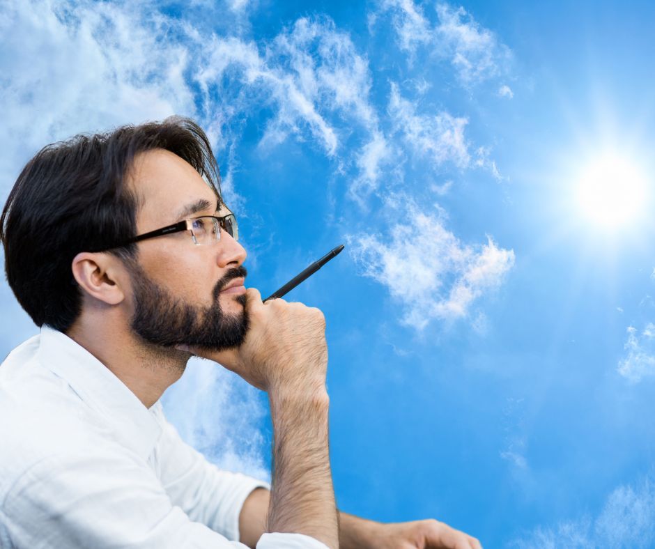 Man holding a pen, looking at sky